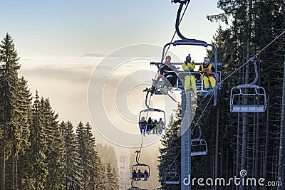 Happy skiers on chairlift above the clouds Editorial Stock Photo